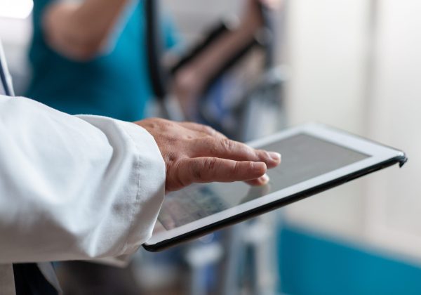 Close up of doctor using digital tablet with touch screen at physical recovery clinic. Medical worker holding modern device and technology to help patient with workout and fitness