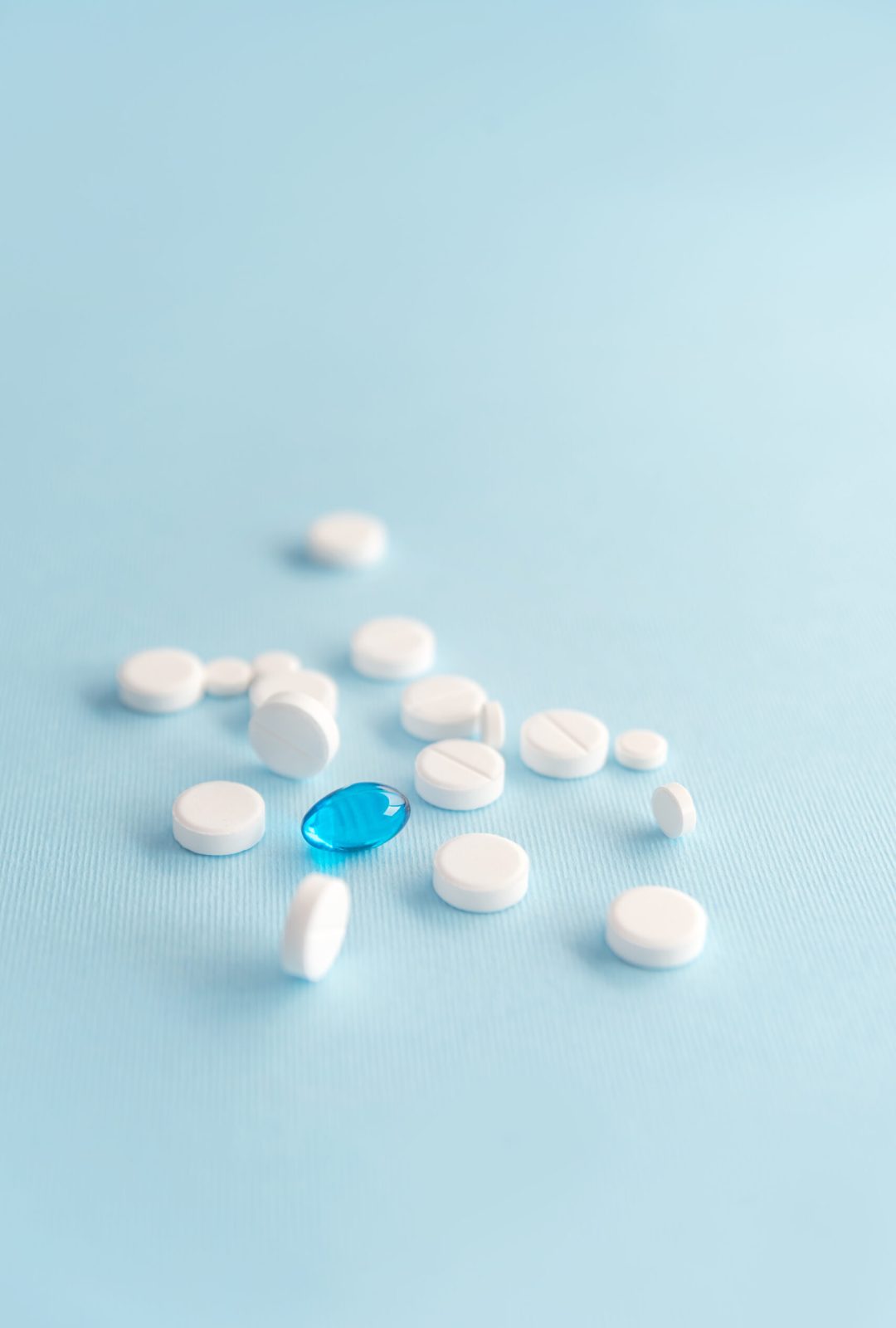 Close up of white tablets with one blue capsule isolated